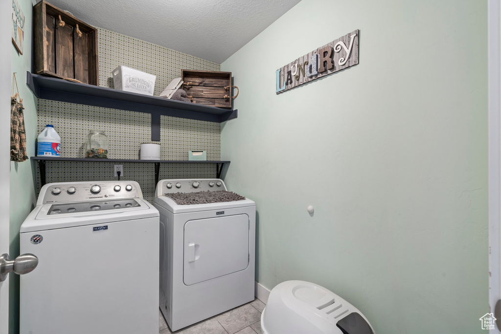 Washroom featuring washing machine and dryer and light tile flooring
