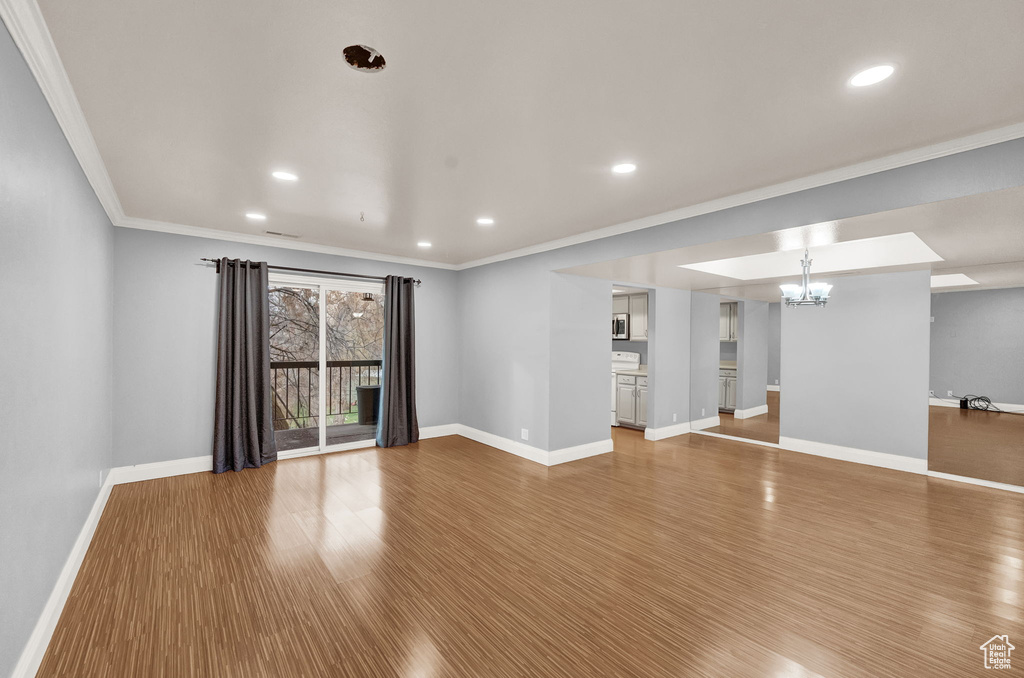 Empty room with a chandelier, crown molding, and light hardwood / wood-style floors