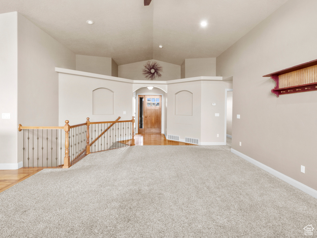 Spare room featuring high vaulted ceiling and light carpet