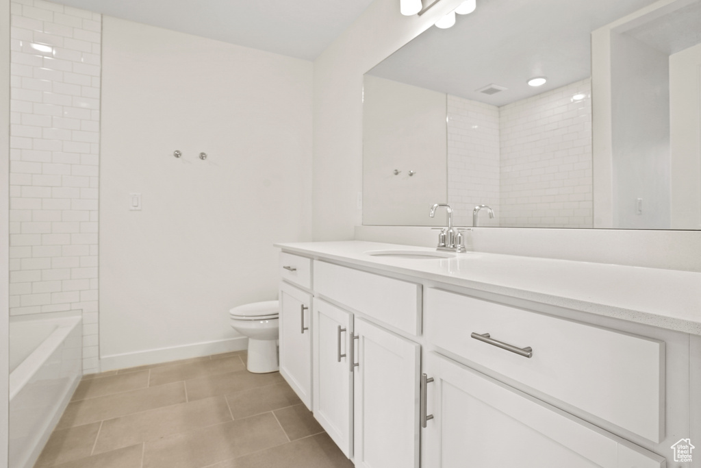 Full bathroom with toilet, vanity with extensive cabinet space, tile flooring, and tiled shower / bath