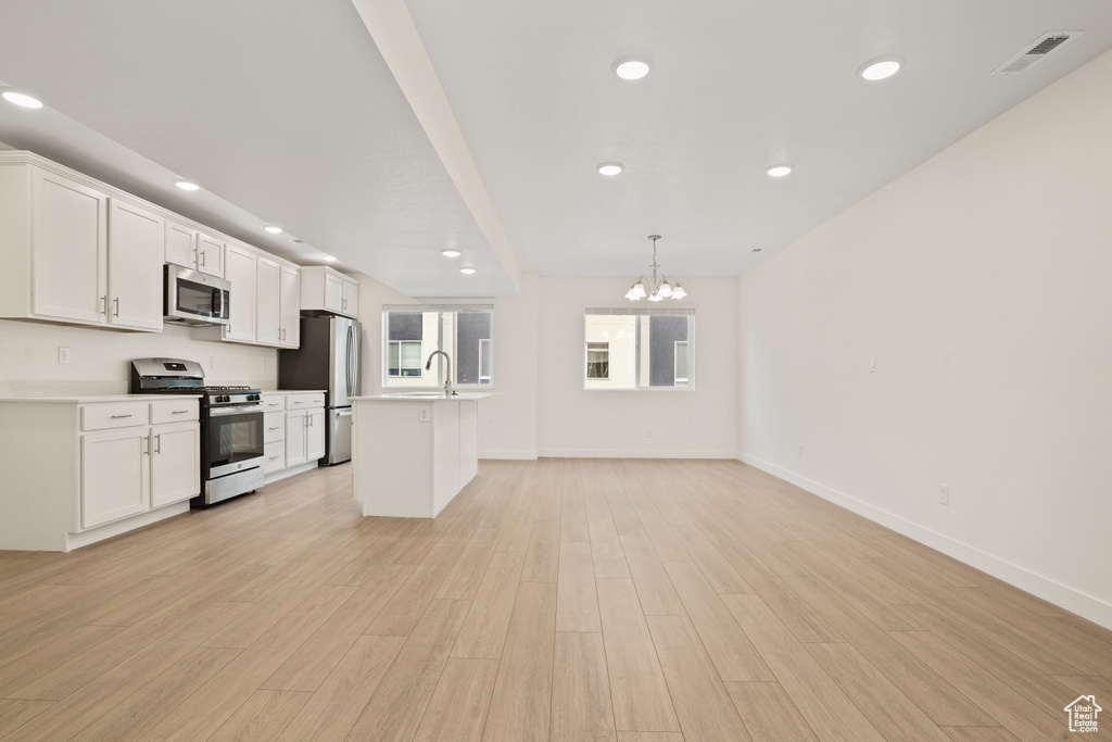 Kitchen featuring an inviting chandelier, white cabinetry, stainless steel appliances, and light hardwood / wood-style floors
