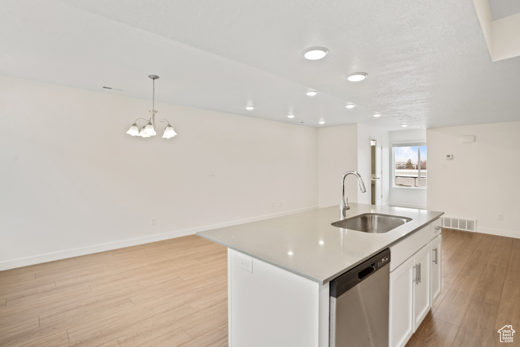 Kitchen with sink, white cabinets, a chandelier, stainless steel dishwasher, and light hardwood / wood-style flooring