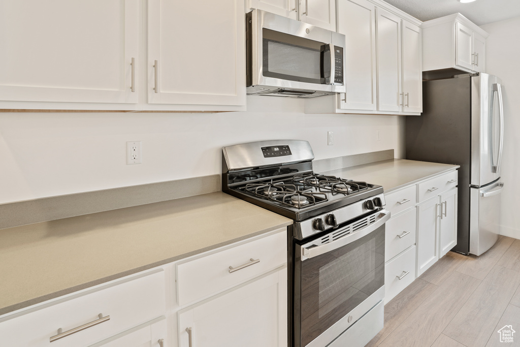 Kitchen featuring white cabinetry, light wood-type flooring, and stainless steel appliances