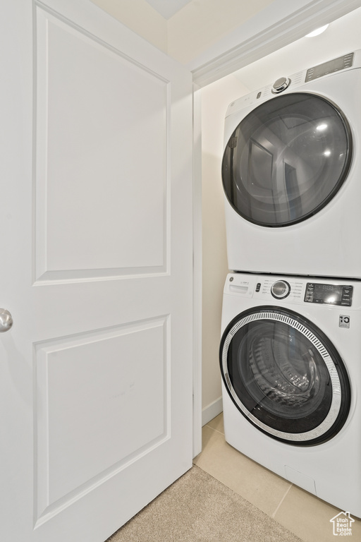 Washroom featuring light tile floors and stacked washer and clothes dryer