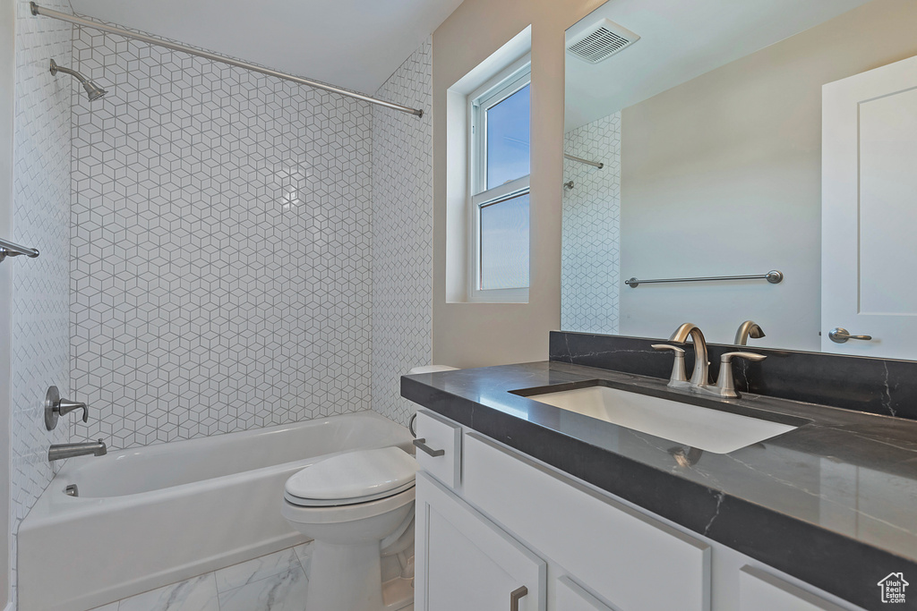 Full bathroom featuring vanity, toilet, tile flooring, and tiled shower / bath combo