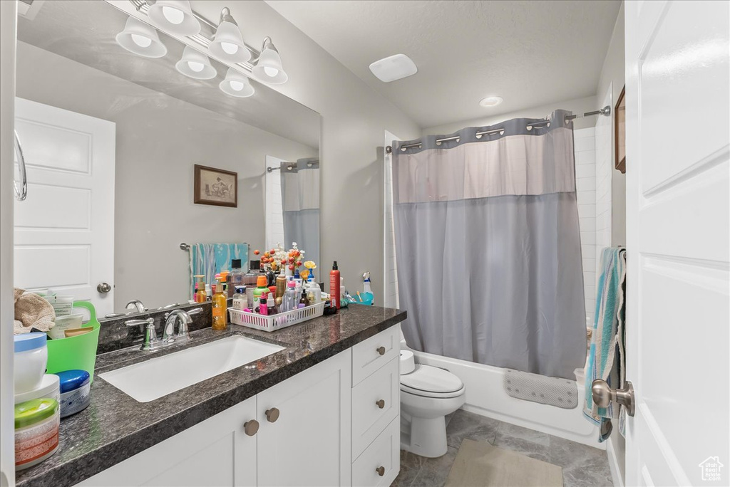 Full bathroom featuring shower / bath combo, tile floors, toilet, and vanity