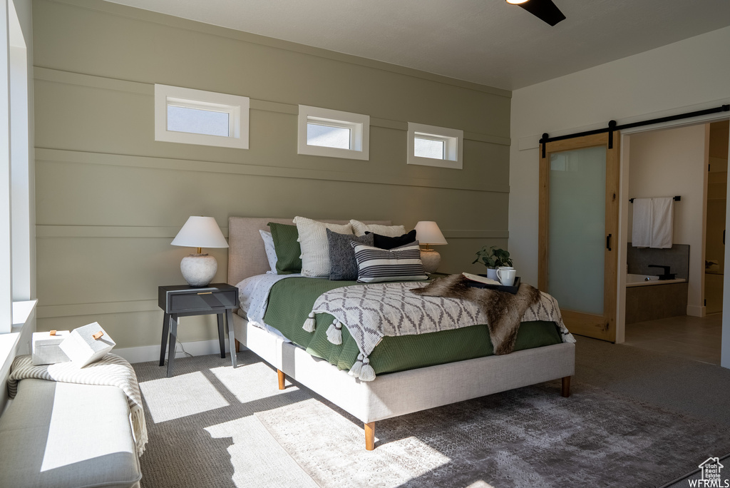 Carpeted bedroom with ceiling fan and a barn door