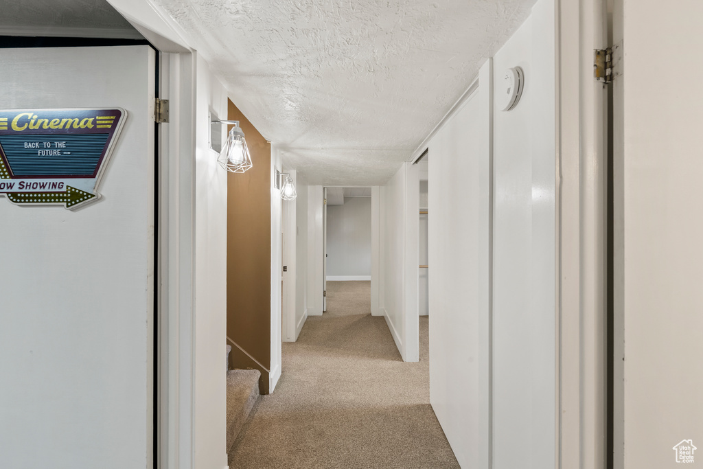 Corridor with light carpet and a textured ceiling