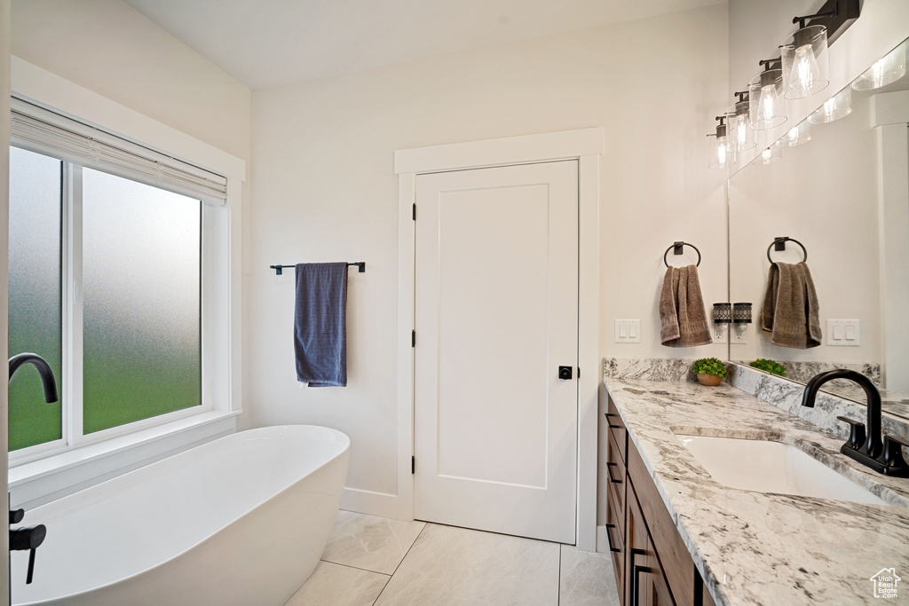 Bathroom featuring vanity with extensive cabinet space, a bathtub, and tile flooring