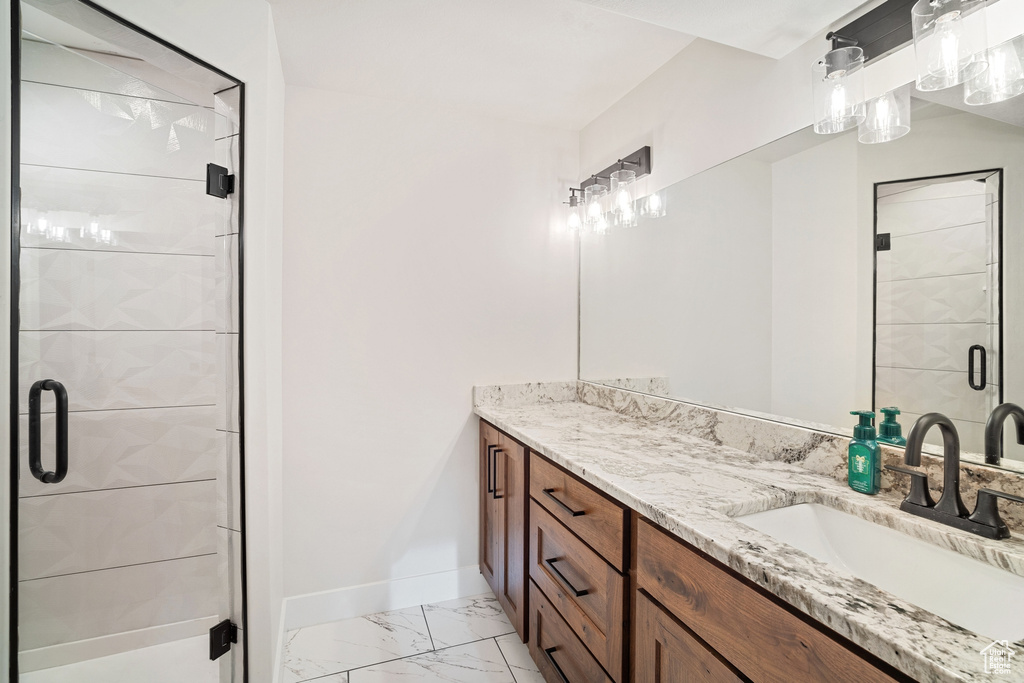Bathroom with tile flooring, dual sinks, vanity with extensive cabinet space, and an enclosed shower