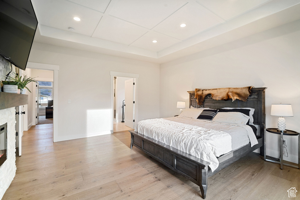 Bedroom with light hardwood / wood-style floors and a tray ceiling