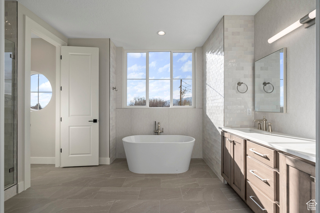 Bathroom with vanity, tile walls, tile flooring, and a bathtub