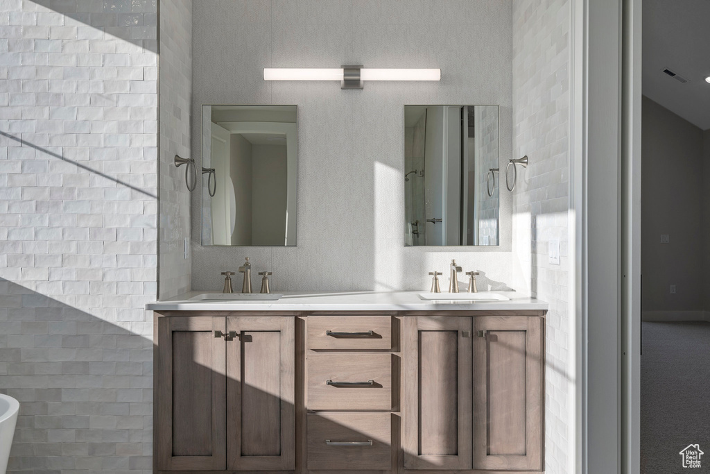 Bathroom featuring dual sinks, tile walls, and large vanity