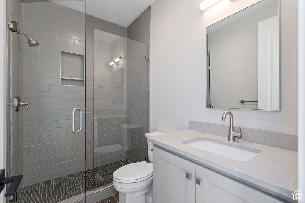 Bathroom featuring tile flooring, toilet, vanity, and walk in shower