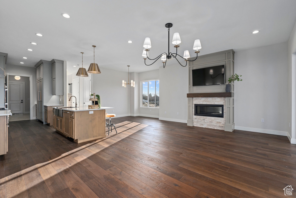 Kitchen with a notable chandelier, hanging light fixtures, sink, and dark wood-type flooring