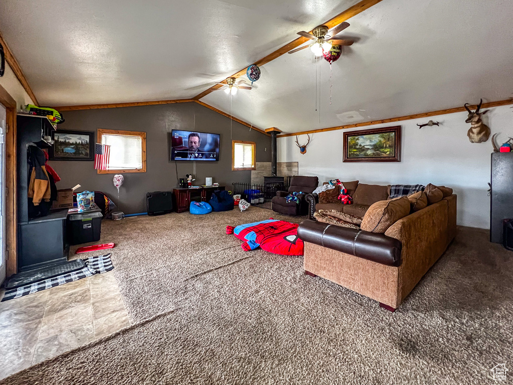 Living room with vaulted ceiling, a wood stove, dark carpet, and ceiling fan