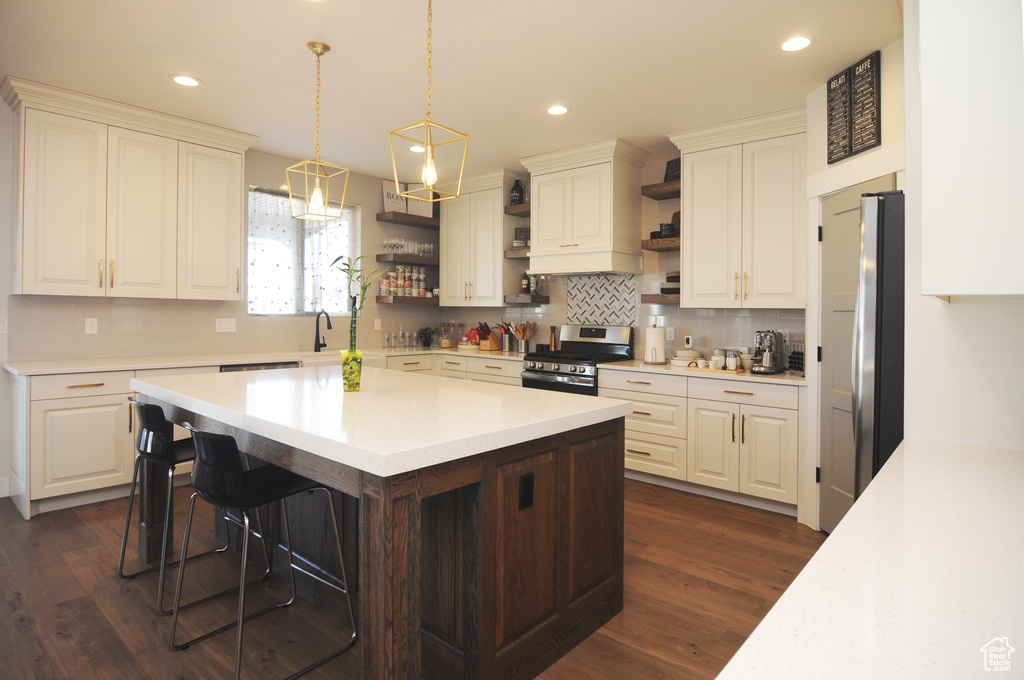 Kitchen with tasteful backsplash, a kitchen bar, dark wood-type flooring, a center island, and stainless steel appliances