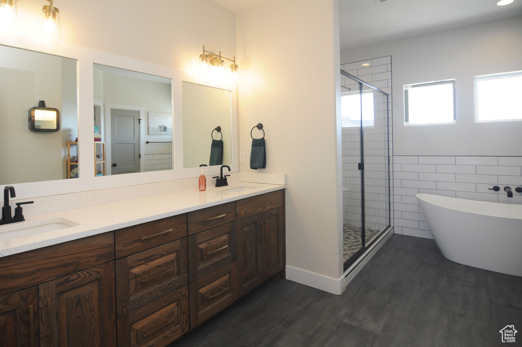 Bathroom featuring dual sinks, vanity with extensive cabinet space, and plus walk in shower