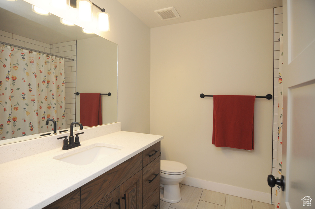 Bathroom featuring tile flooring, oversized vanity, and toilet