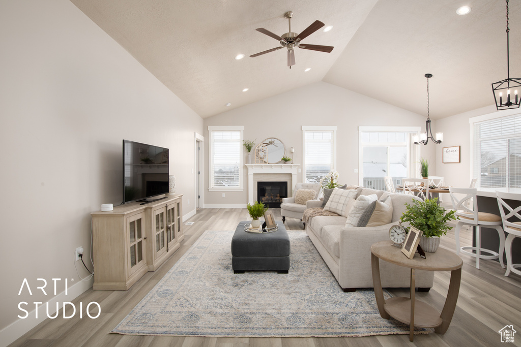 Living room featuring high vaulted ceiling, light hardwood / wood-style floors, and ceiling fan with notable chandelier