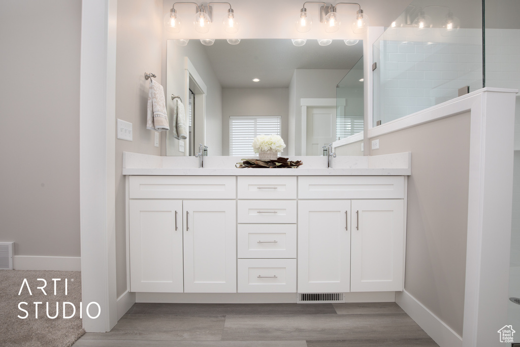 Bathroom with dual vanity and hardwood / wood-style floors