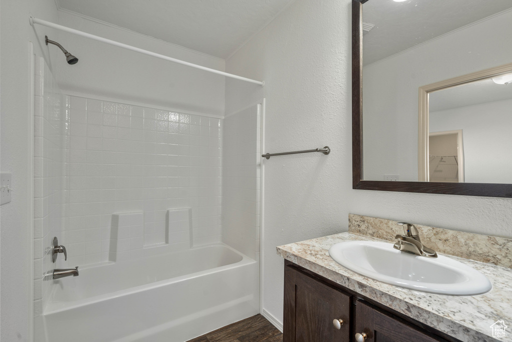 Bathroom with shower / bathtub combination, oversized vanity, and wood-type flooring