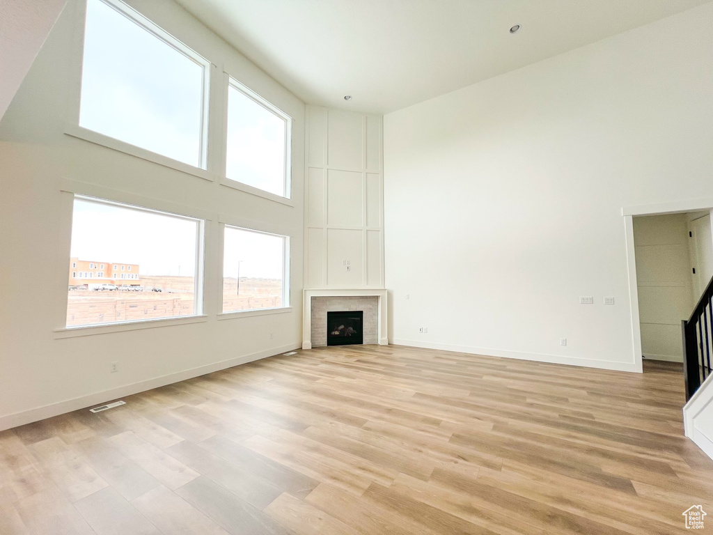 Unfurnished living room featuring light hardwood / wood-style flooring and a towering ceiling