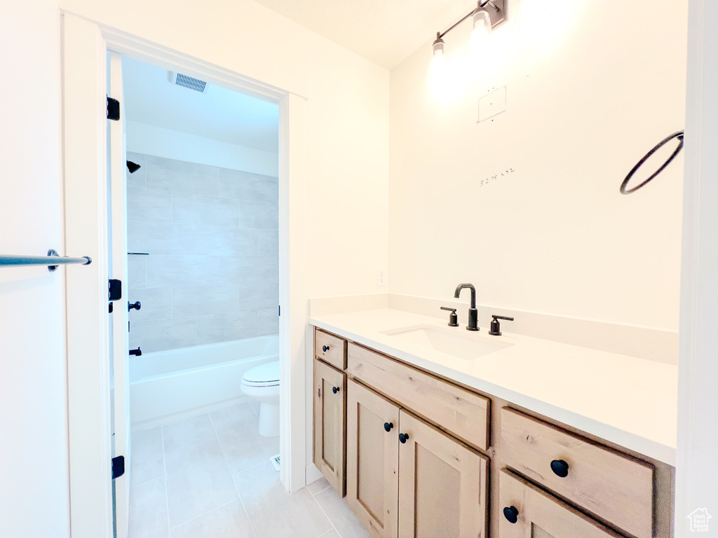 Full bathroom with vanity, toilet, tile flooring, and tiled shower / bath