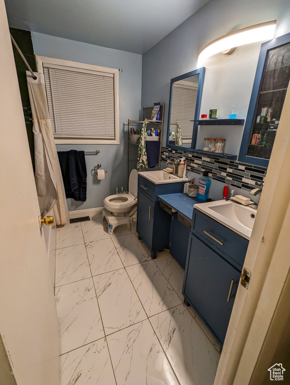 Bathroom featuring toilet, tile flooring, large vanity, and backsplash