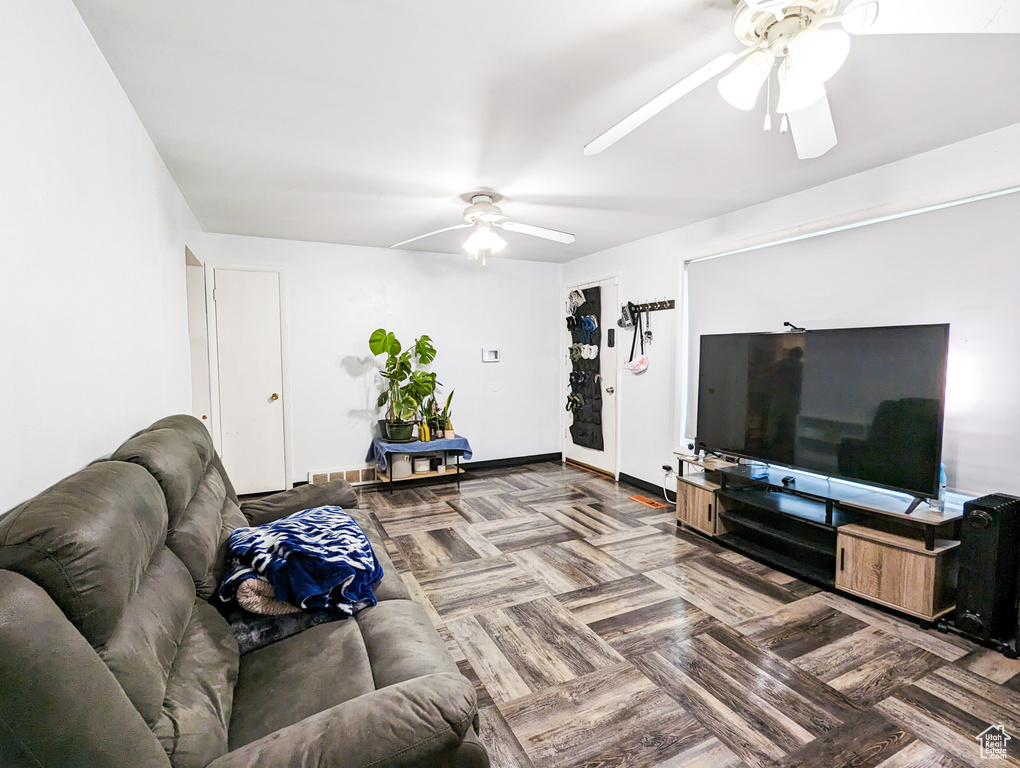 Living room with ceiling fan and dark parquet floors