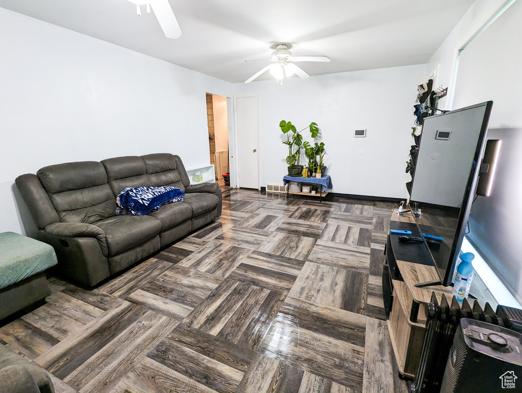 Living room featuring dark parquet flooring and ceiling fan