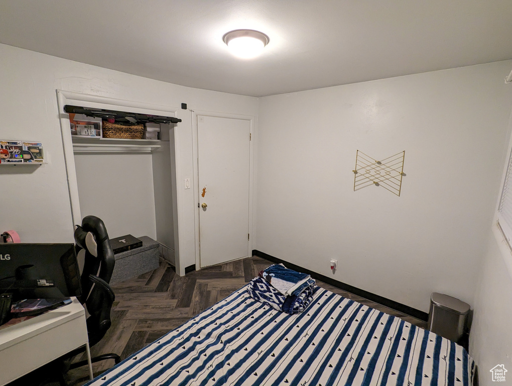 Bedroom with dark parquet flooring and a closet