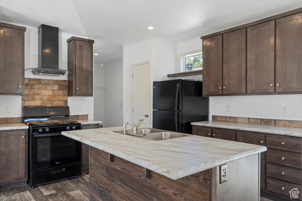 Kitchen featuring sink, dark brown cabinetry, dark hardwood / wood-style flooring, black appliances, and wall chimney exhaust hood