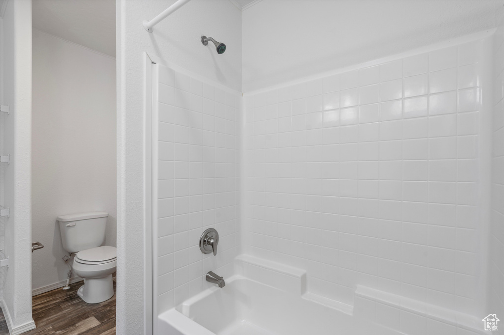 Bathroom with toilet, shower / tub combination, and hardwood / wood-style floors