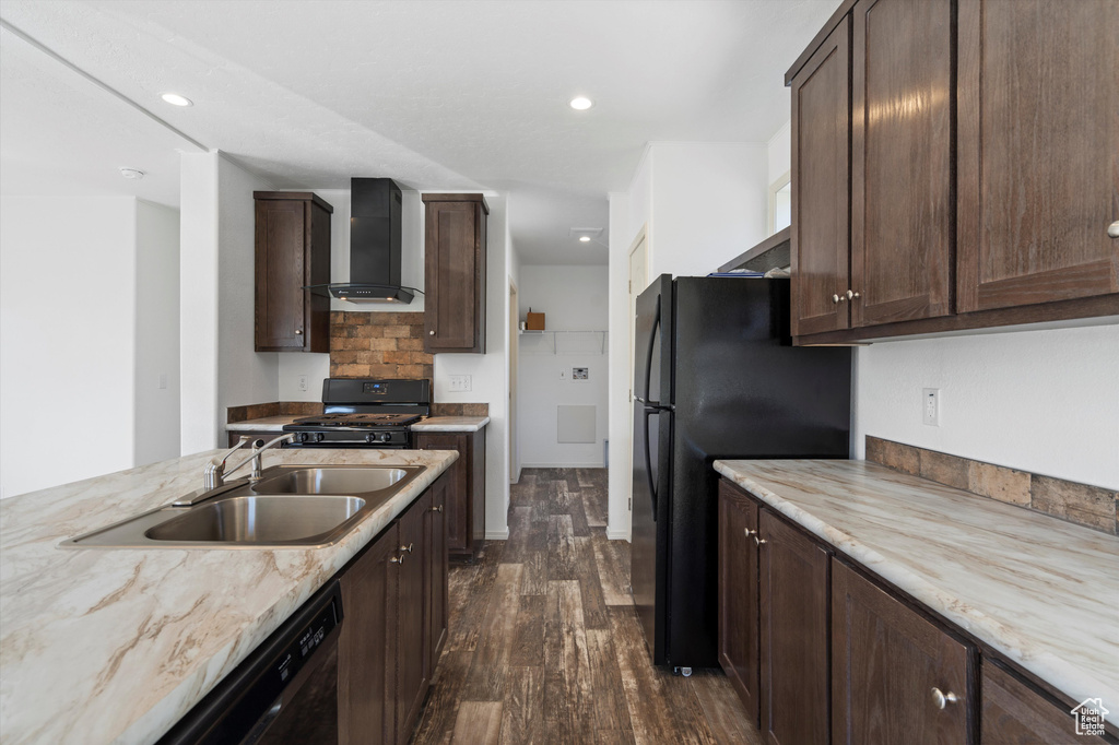 Kitchen featuring dark hardwood / wood-style floors, dark brown cabinetry, wall chimney exhaust hood, black appliances, and light stone countertops