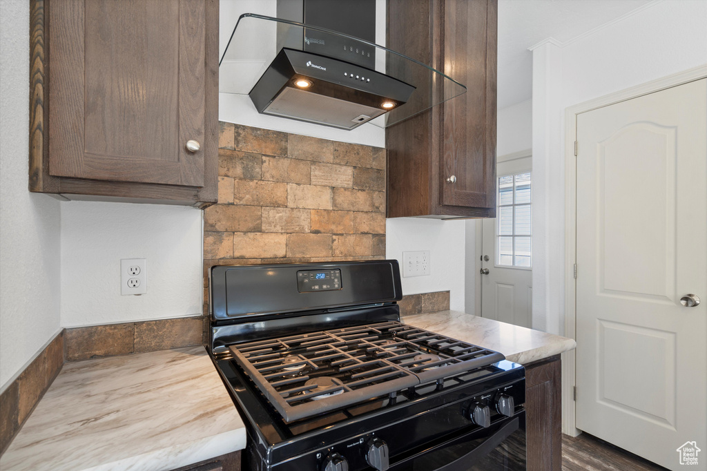 Kitchen featuring wood-type flooring, range with gas cooktop, dark brown cabinets, and ventilation hood