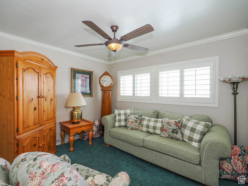 Living room featuring dark colored carpet, crown molding, and ceiling fan