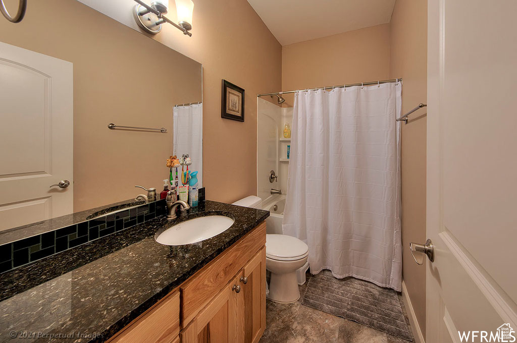 Full bathroom featuring toilet, shower / tub combo, tile flooring, and large vanity