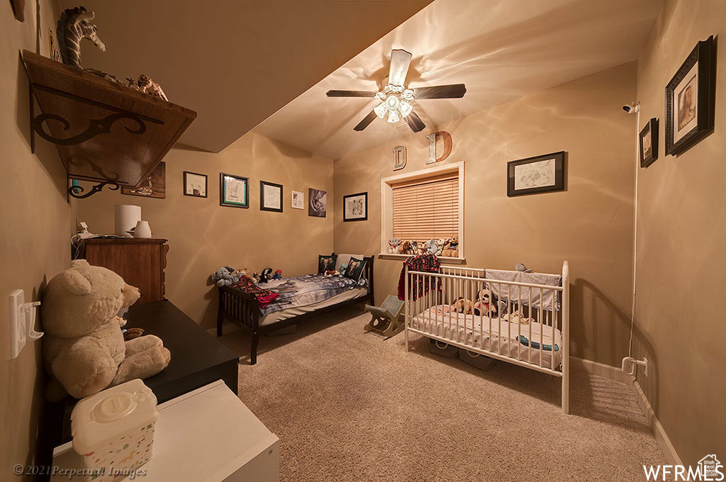 Carpeted bedroom with ceiling fan and a nursery area