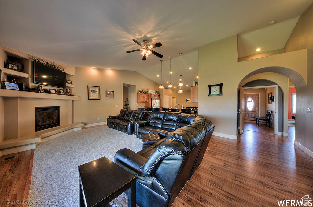 Living room featuring dark wood-type flooring, vaulted ceiling, and ceiling fan