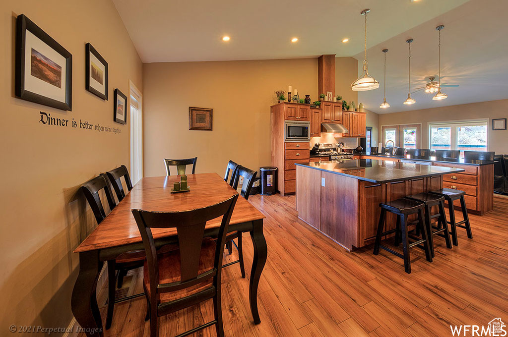 Dining room featuring sink, light wood-type flooring, ceiling fan, and lofted ceiling