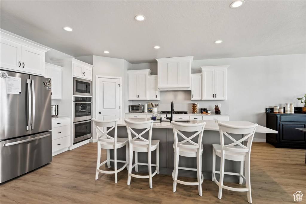 Kitchen featuring light wood-type flooring, white cabinets, and stainless steel appliances