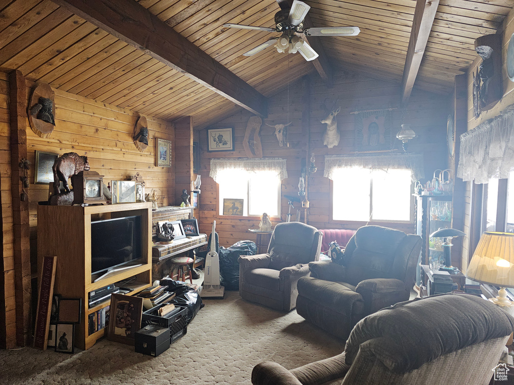 Living room featuring vaulted ceiling with beams, ceiling fan, wooden walls, wood ceiling, and carpet flooring