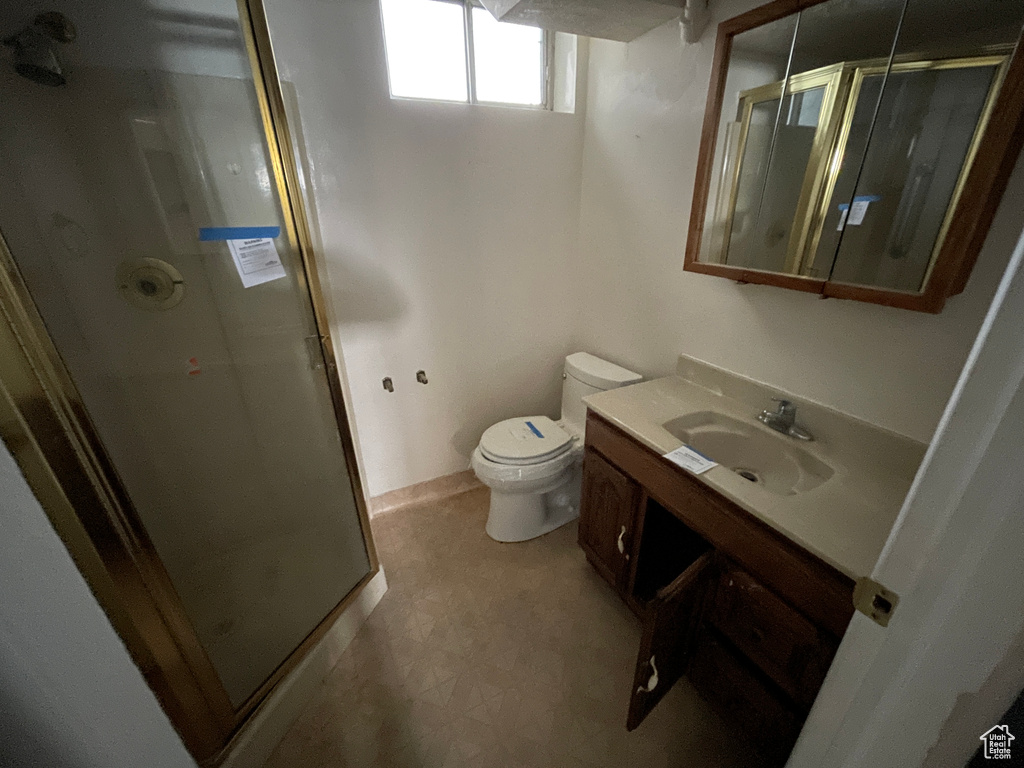Bathroom featuring an enclosed shower, tile floors, toilet, and vanity