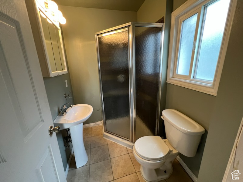 Bathroom with tile flooring, a shower with door, and toilet