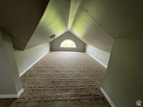 Additional living space featuring lofted ceiling and dark carpet