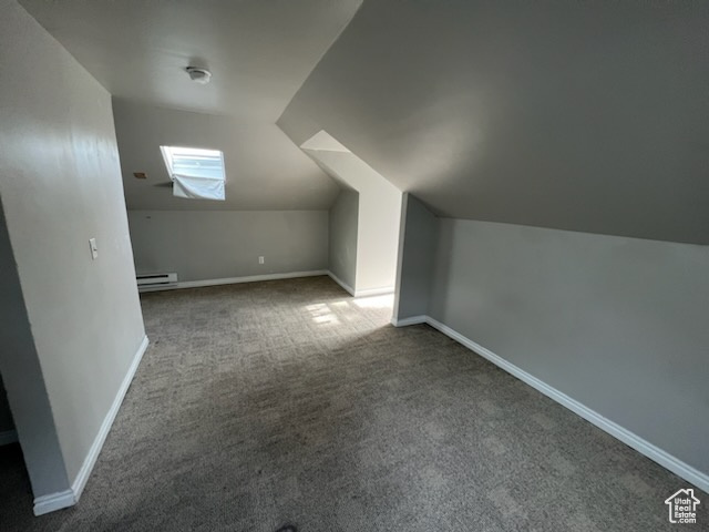 Additional living space featuring vaulted ceiling, baseboard heating, and dark carpet