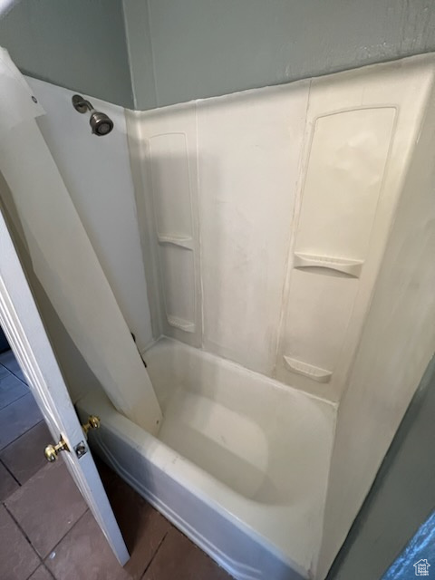 Bathroom with tile flooring and washtub / shower combination