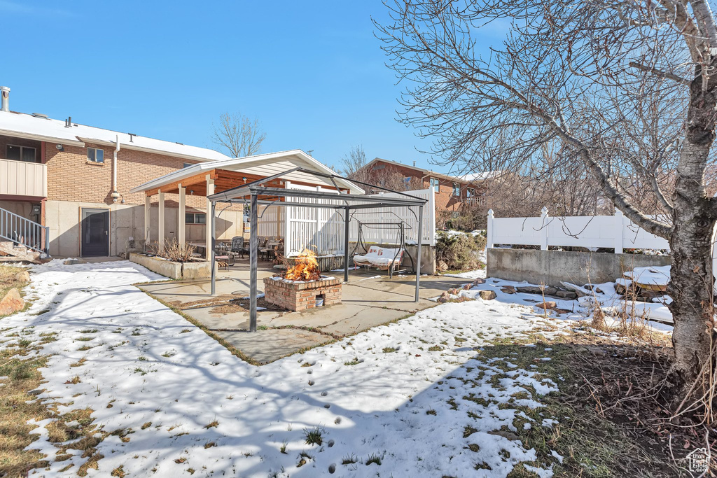 Snow covered back of property with an outdoor fire pit, a patio area, and a gazebo