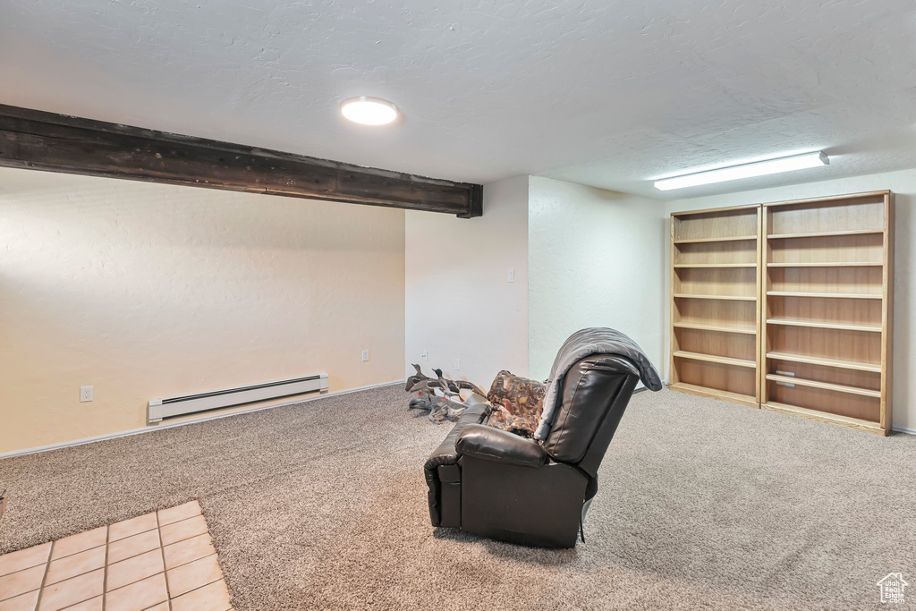 Interior space with light carpet, a baseboard heating unit, and beamed ceiling